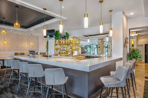 A modern bar area with a central island, bar stools, and hanging pendant lights. - Chateau Cartier Hotel & Resort, an Ascend Collection Resort (Gatineau)