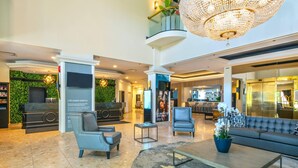 A lobby with a reception desk, seating area, chandelier, and a staircase. - Chateau Cartier Hotel & Resort, an Ascend Collection Resort (Gatineau)