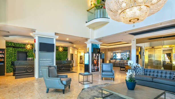 Un vestíbulo con mostrador de recepción, zona de estar, candelabro y una escalera.