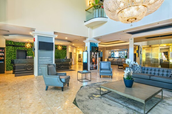 A lobby with a reception desk, seating area, chandelier, and a staircase. - Chateau Cartier Hotel & Resort, an Ascend Collection Resort (Gatineau)