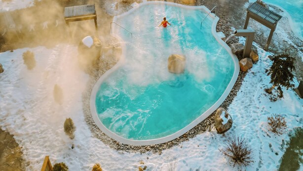 A hot tub surrounded by snow, with a person in the water. - Chateau Cartier Hotel & Resort, an Ascend Collection Resort (Gatineau)