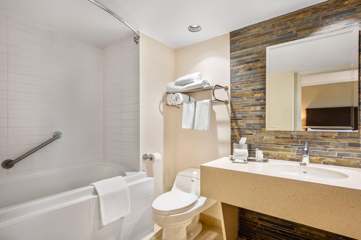 A bathroom with a shower, toilet, sink, and a towel rack.