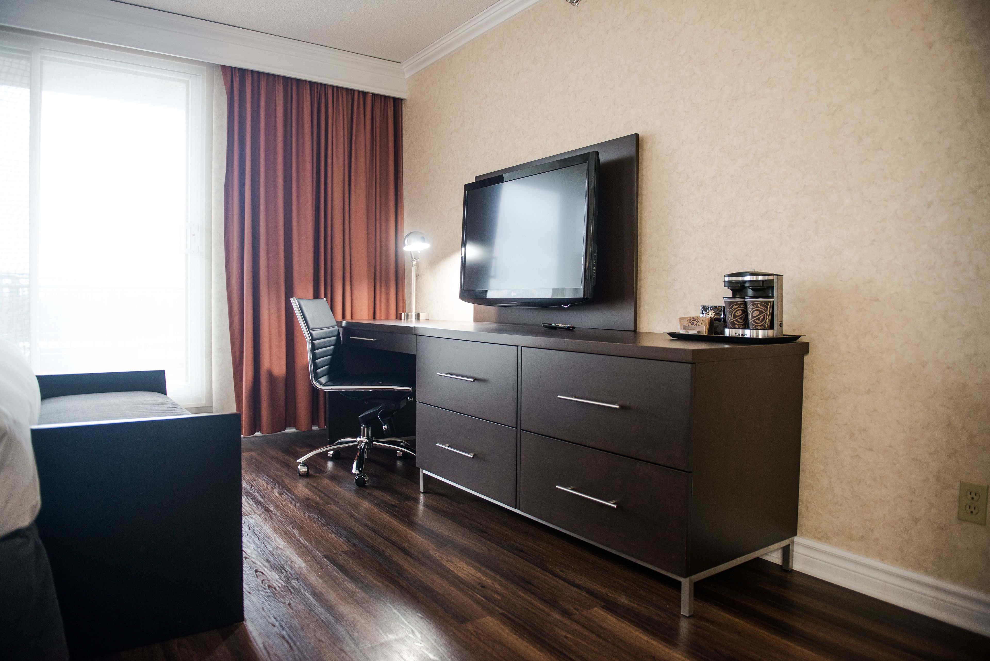 Une chambre d’hôtel équipée d’un lit, d’un bureau avec une chaise, d’une télévision et d’une machine à café.