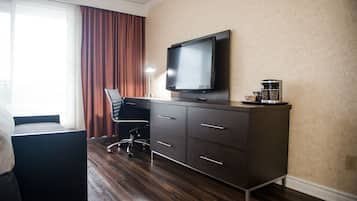 Une chambre d’hôtel équipée d’un lit, d’un bureau avec une chaise, d’une télévision et d’une machine à café.