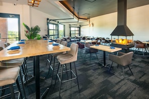 Une salle de conférence spacieuse, dotée d’une longue table, de nombreuses chaises et d’une grande cheminée.
