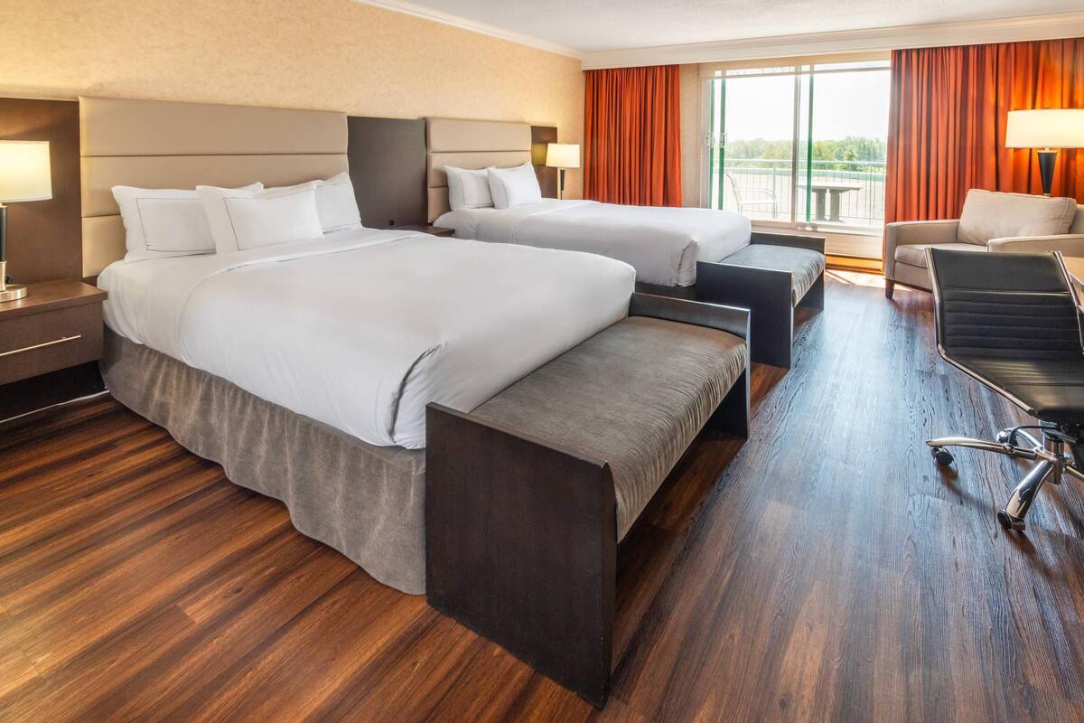 Une chambre d’hôtel avec deux lits, un canapé, un bureau et une chaise.