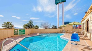 Un área de piscina con un cartel de LaQuindy Inn, un letrero que indica que no se permite bucear y sillas de descanso.