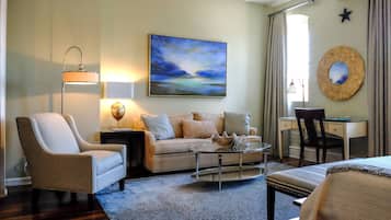 A cozy living room with a sofa, armchair, coffee table, and a painting on the wall.