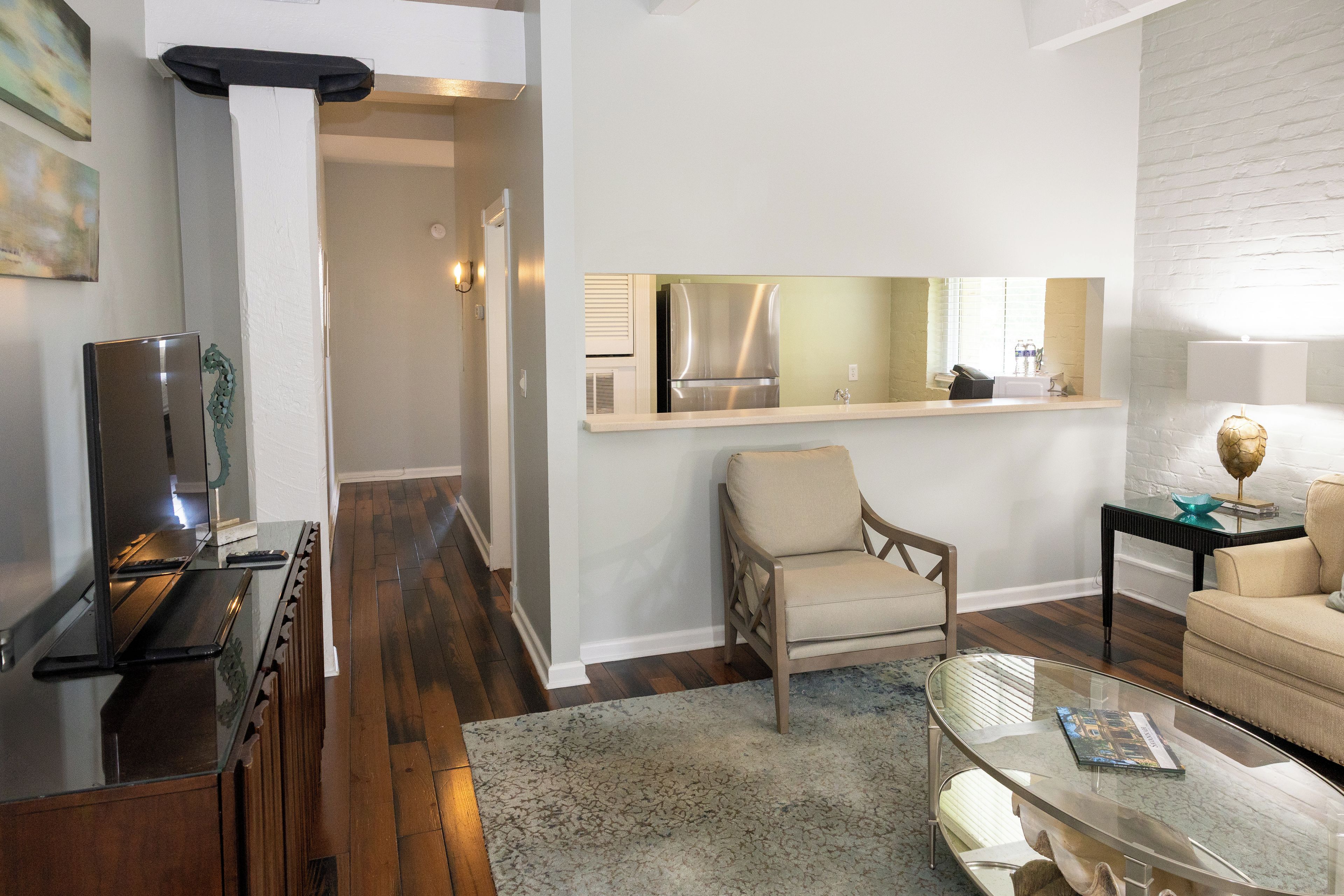 Una sala de estar moderna con un sofá, una mesa de centro de vidrio y un comedor con una mesa y sillas.