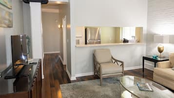 Una sala de estar moderna con un sofá, una mesa de centro de vidrio y un comedor con una mesa y sillas.