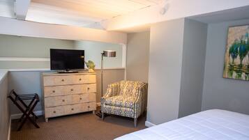 Un dormitorio con cama, cómoda, silla, televisor y un cuadro en la pared.