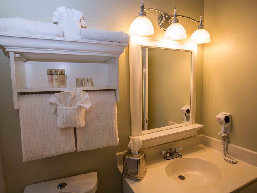 Un baño con lavamanos, espejo, toallero y secador de pelo.