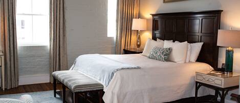A neatly arranged bedroom with a large bed, two bedside tables with lamps, a bench, and a star decoration on the wall.