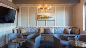 A cozy seating area with a bench, two armchairs, and a small table with glasses and a bottle. - Olde Harbour Inn (Savannah)