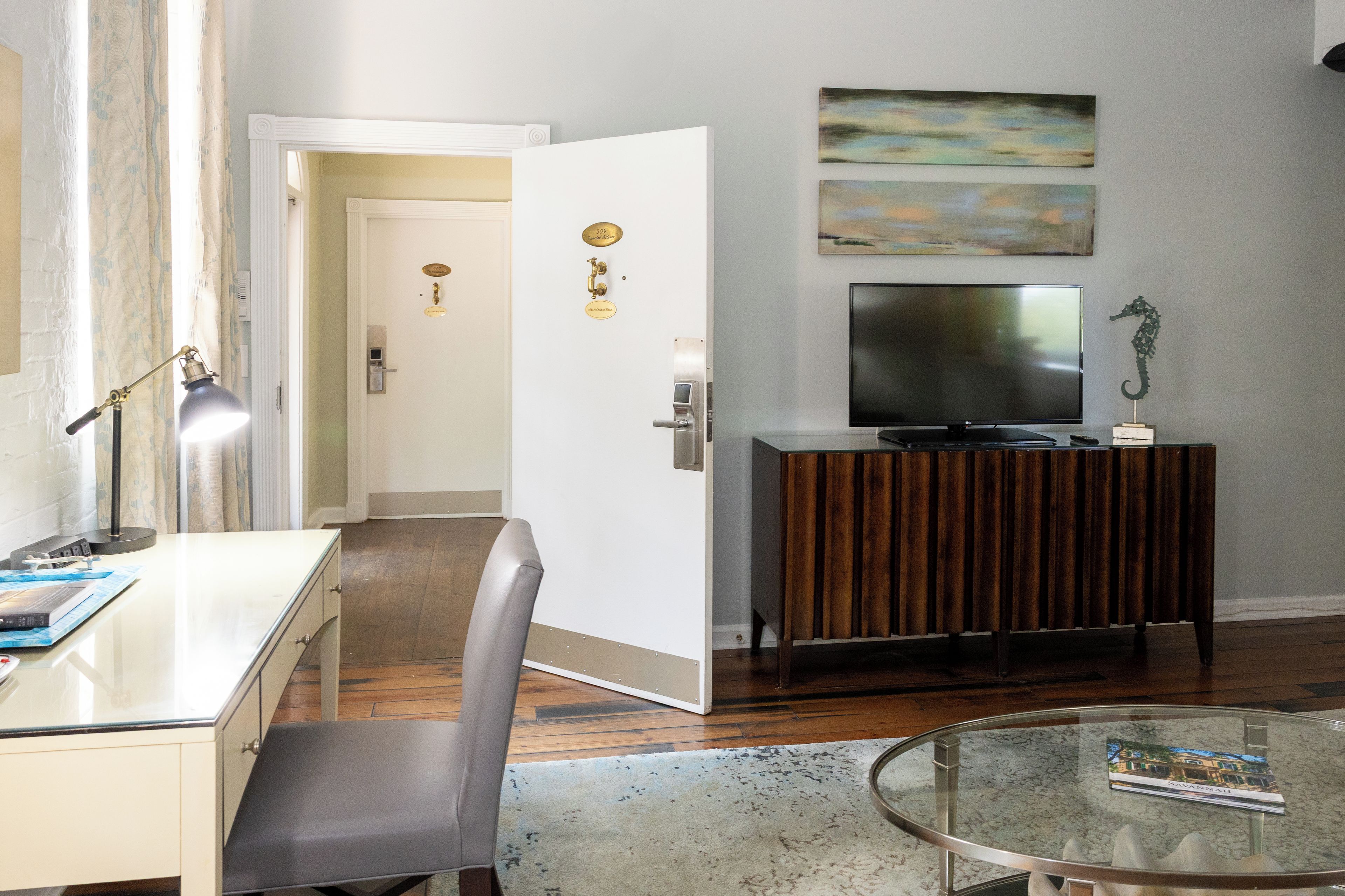 A modern living room with a flat-screen TV, a glass coffee table, and a seating area with a chair.