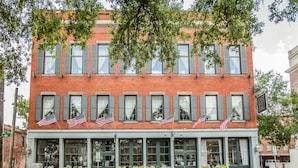 A brick building with multiple windows and American flags. - East Bay Inn, Historic Inns of Savannah Collection (Savannah)