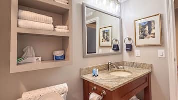 A bathroom with a toilet, sink, and shelves with towels.