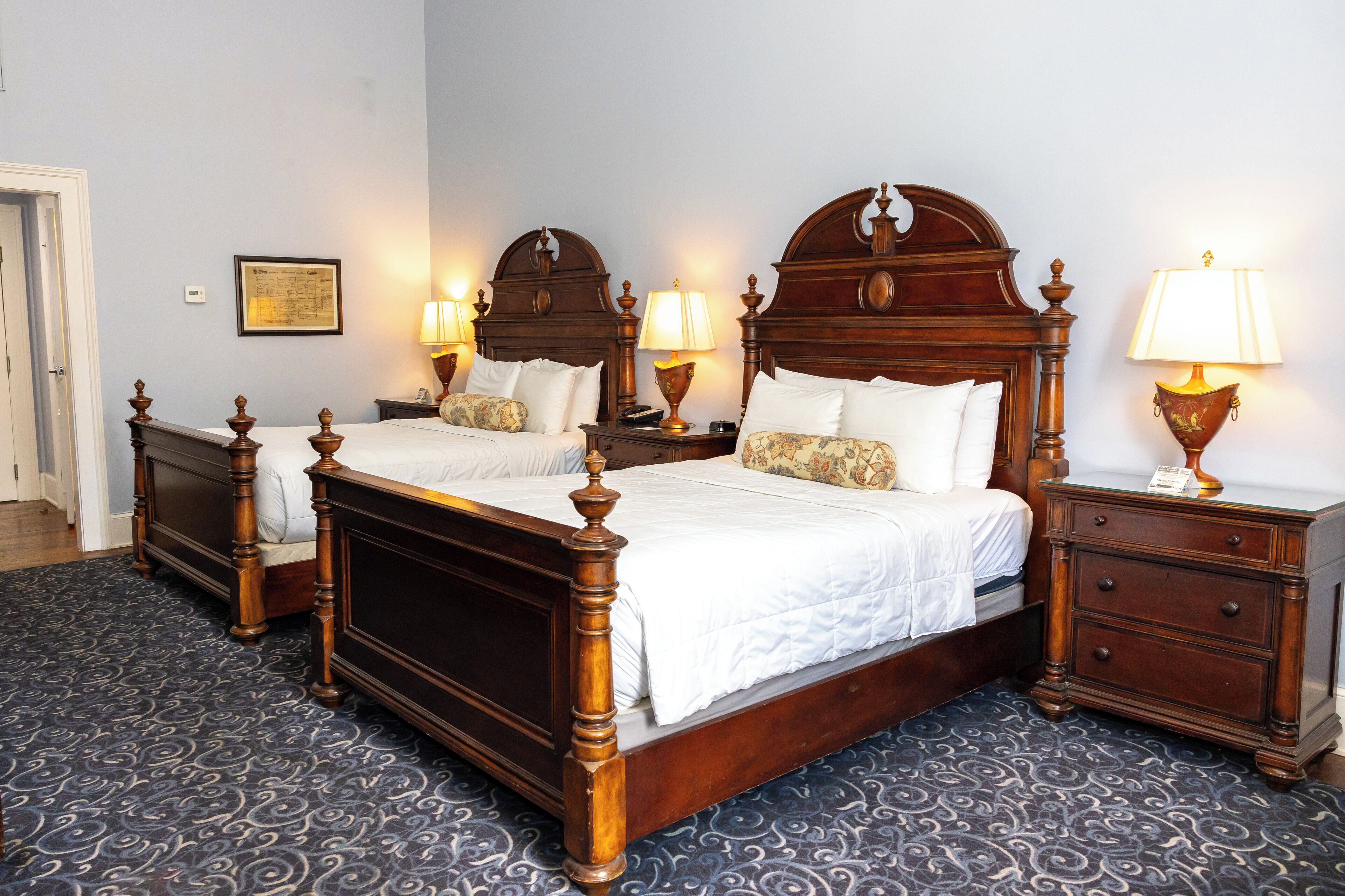 A double bed with a wooden headboard, two bedside tables with lamps, and a patterned carpet.