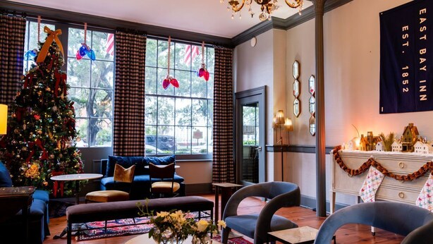 A cozy hotel lobby with a Christmas tree, seating area, and a chandelier. - East Bay Inn, Historic Inns of Savannah Collection (Savannah)