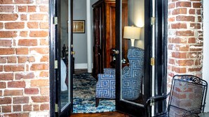 A doorway leading to a room with a patterned chair, a lamp, and a wooden cabinet. - East Bay Inn, Historic Inns of Savannah Collection (Savannah)
