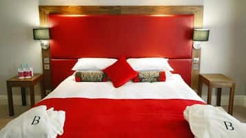 Una habitación de hotel con un cabecero rojo, ropa de cama blanca y dos mesitas de noche con lámparas.