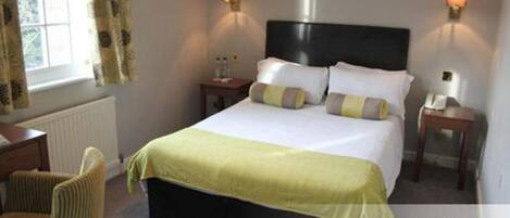 A standard double room with a bed, two bedside tables, a chair, and a window with curtains.