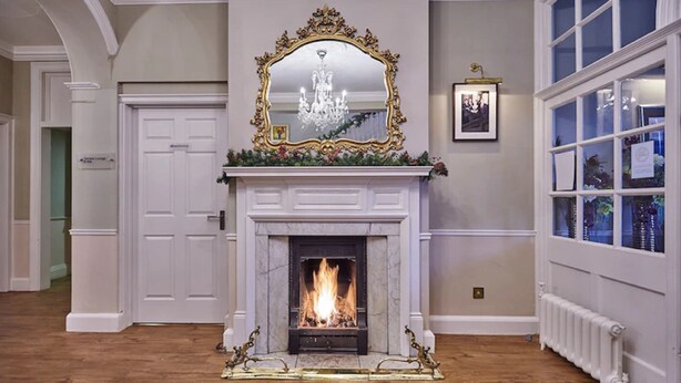 Una habitación con chimenea, un espejo grande encima y una ventana con vistas.