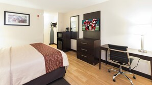 A hotel room with a bed, a desk, a chair, a television, and a small refrigerator. - Red Roof Inn Columbus - Ohio State Fairgrounds (Columbus)