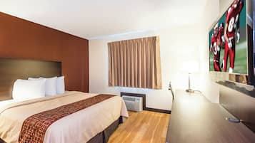 Une chambre d’hôtel équipée d’un lit, d’un bureau, d’une lampe, d’un appareil de climatisation et d’une fenêtre avec des rideaux.