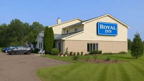 A Royal Inn building with a sign, a parking lot, and a lawn. - Royal Inn & Suites (Milaca)