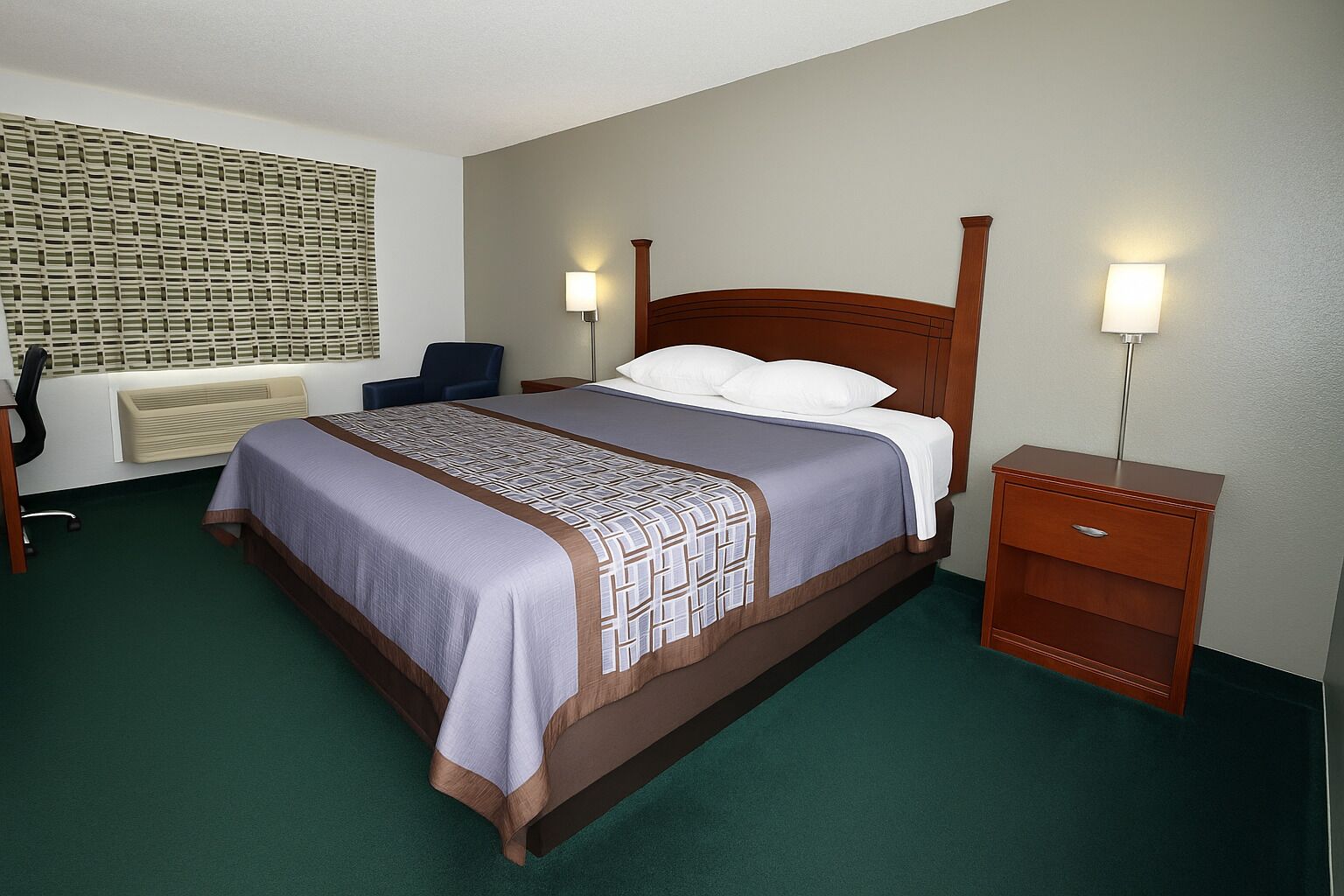 Quarto de hotel com uma cama grande, duas mesinhas de cabeceira, uma cadeira, um radiador e um candeeiro fixado na parede.