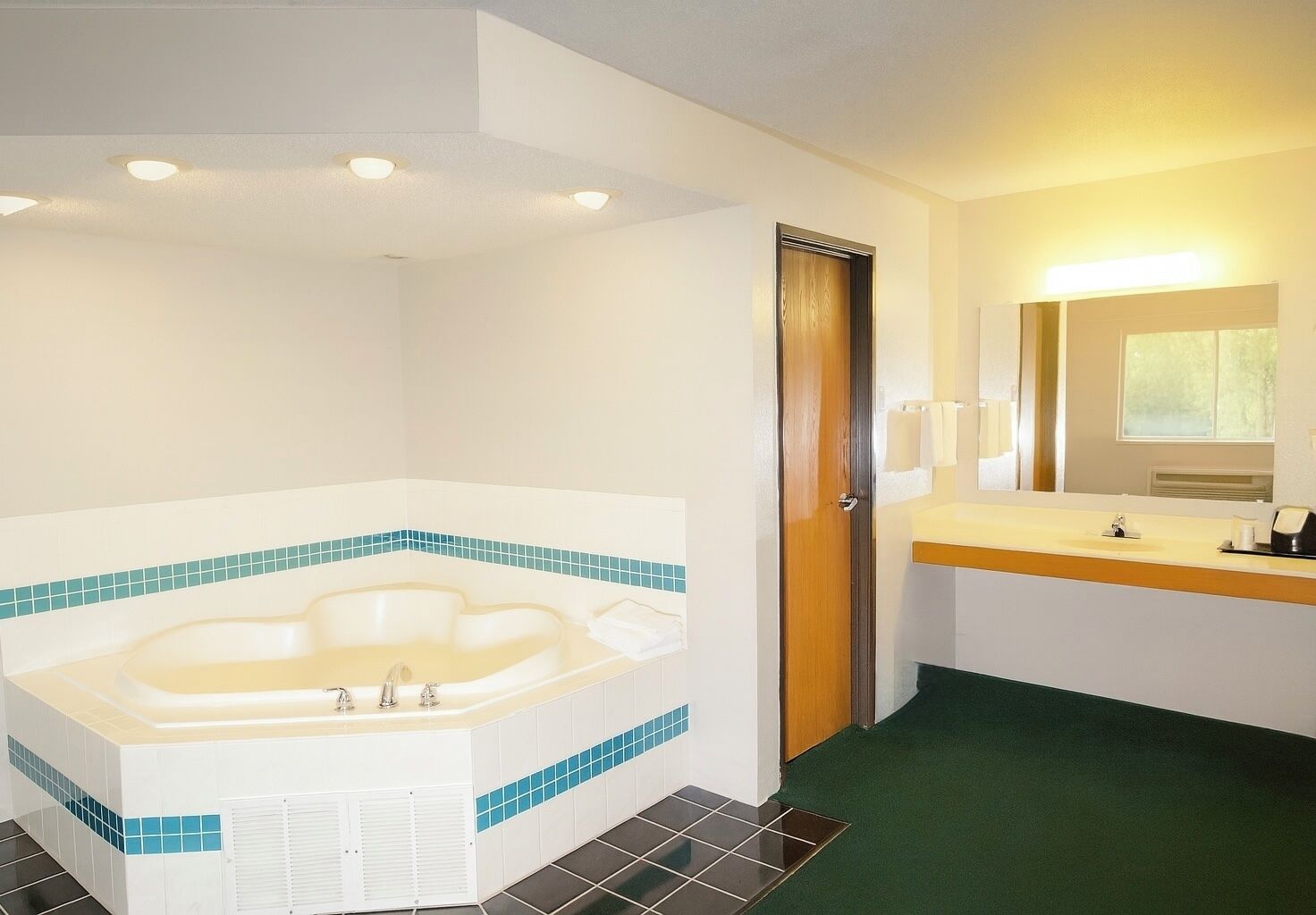 A bathroom with a large bathtub, a sink, and a mirror.
