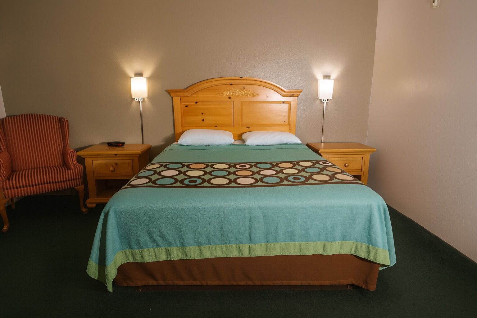A standard hotel room with a bed, two bedside lamps, a chair, and a nightstand.