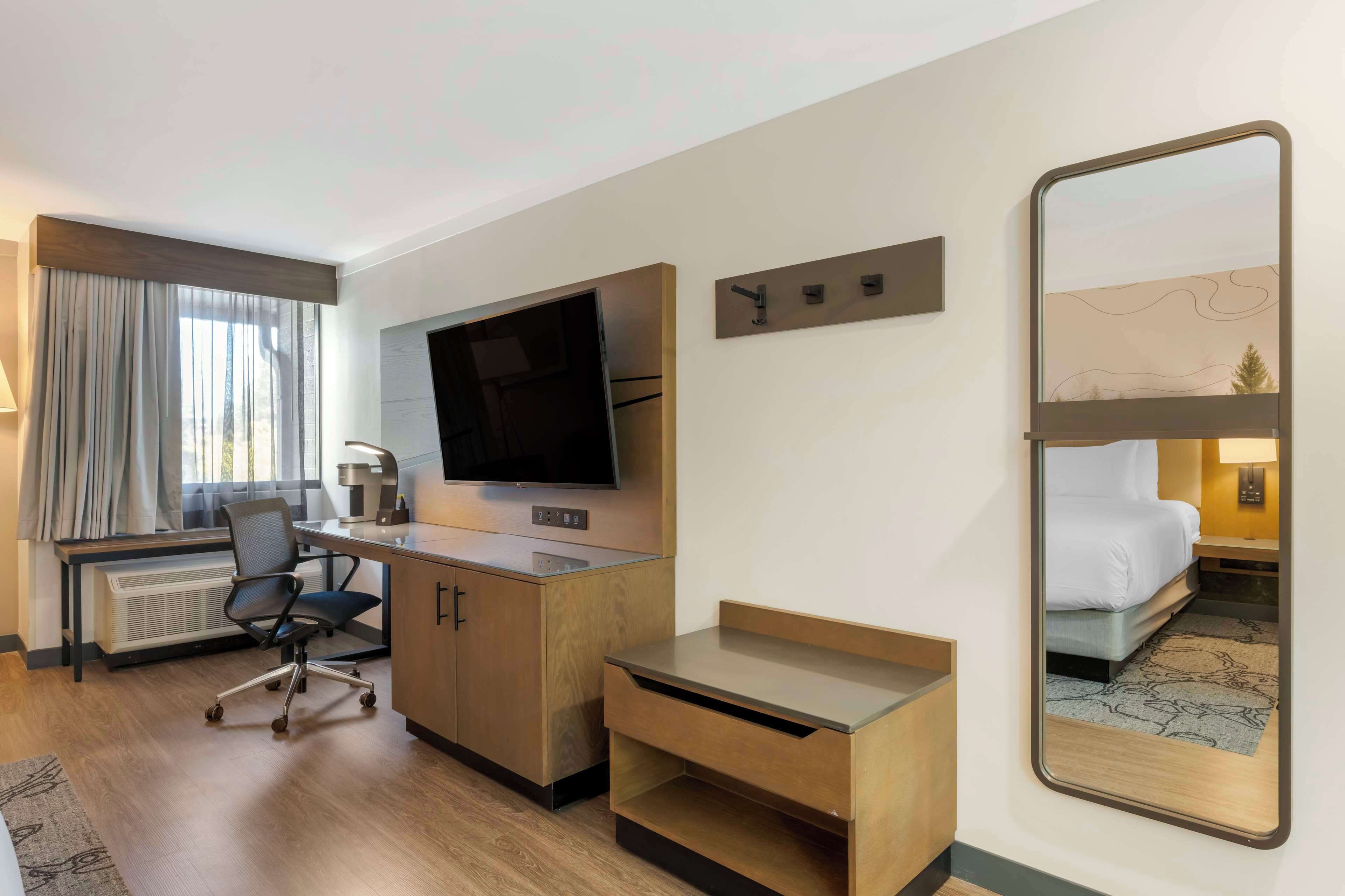Ein Hotelzimmer mit Schreibtisch, Stuhl, Fernseher und Bett.