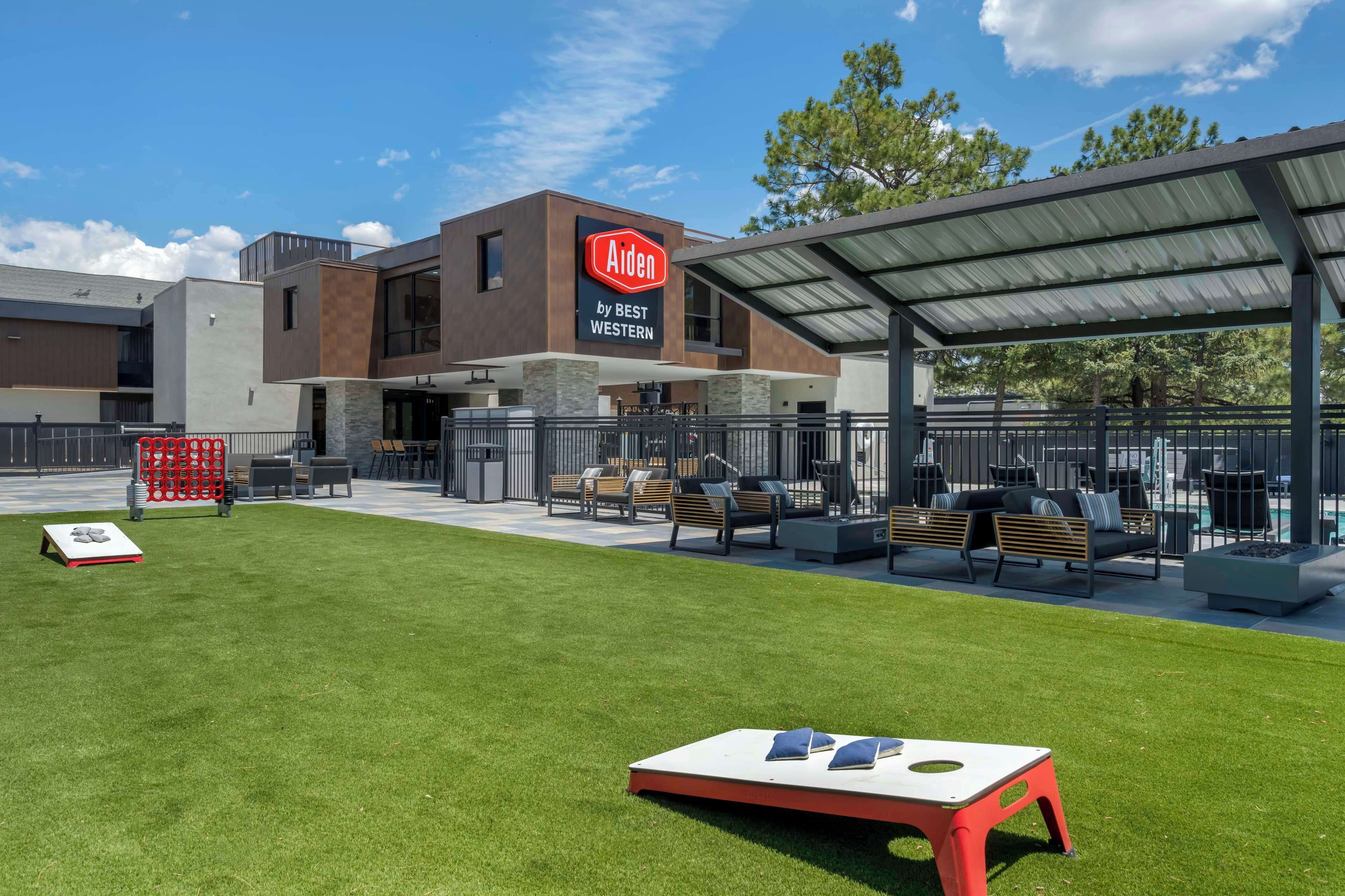 Un moderno hotel Aiden de Best Western con una zona de estar cubierta al aire libre y un césped bien cuidado.