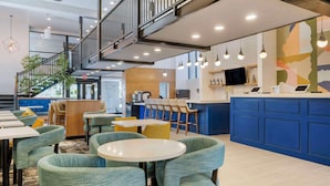 A modern restaurant with a staircase, seating area, and a counter with a TV. - Aiden by Best Western Flagstaff (Flagstaff)