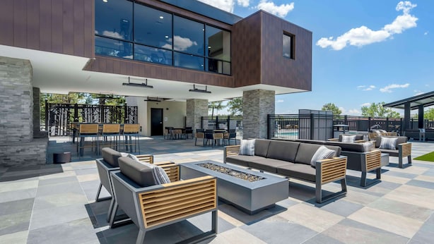 A modern outdoor patio with seating and a fire feature, set against a building with large windows and stone pillars. - Aiden by Best Western Flagstaff (Flagstaff)