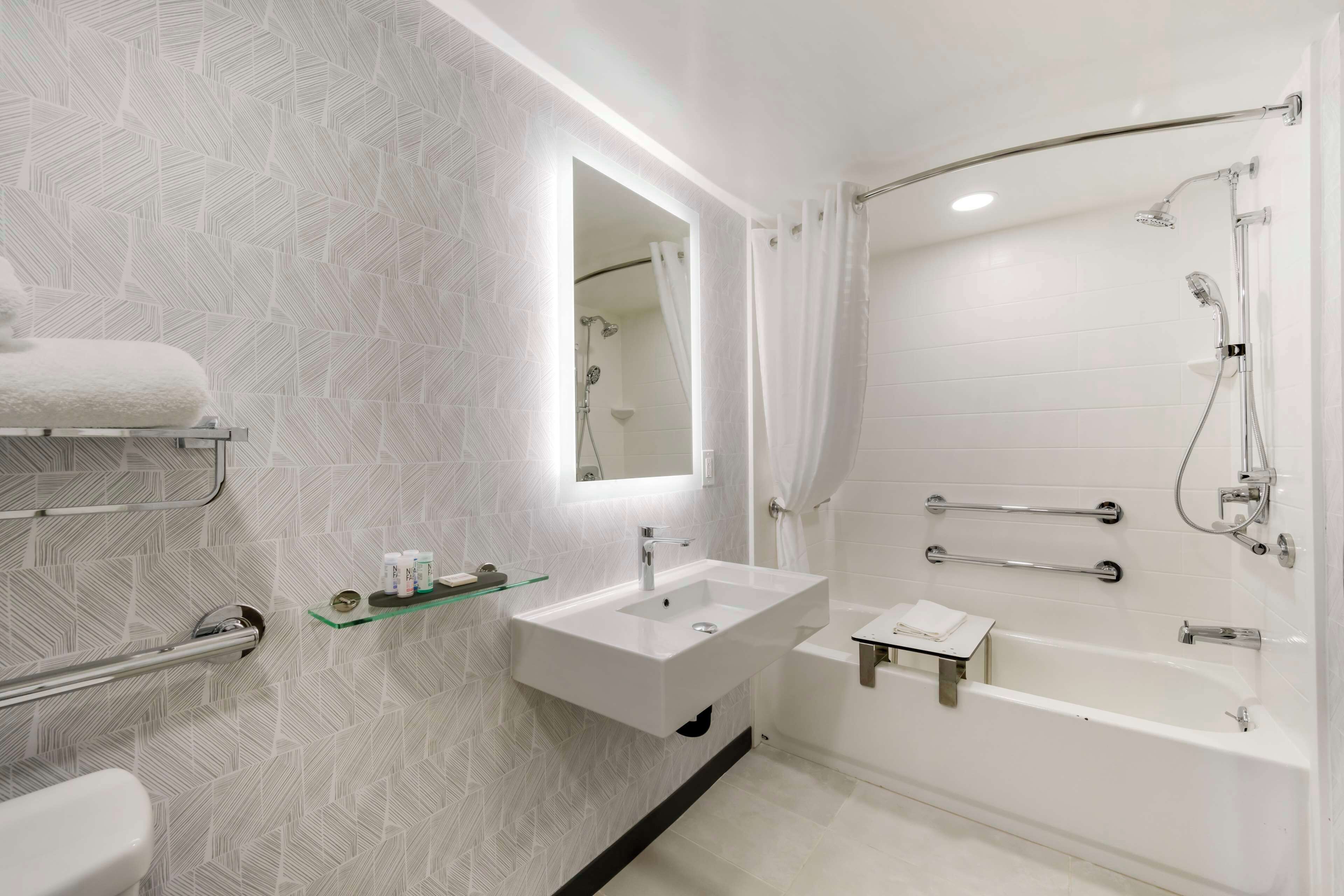 Een moderne badkamer met een wit wastafelmeubel, spiegel en douche.