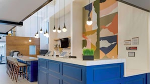 A modern reception area with a blue counter, bar stools, and a large abstract wall mural. - Aiden by Best Western Flagstaff (Flagstaff)