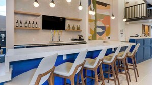 A modern kitchen with a bar area, bar stools, and a TV mounted above the counter. - Aiden by Best Western Flagstaff (Flagstaff)