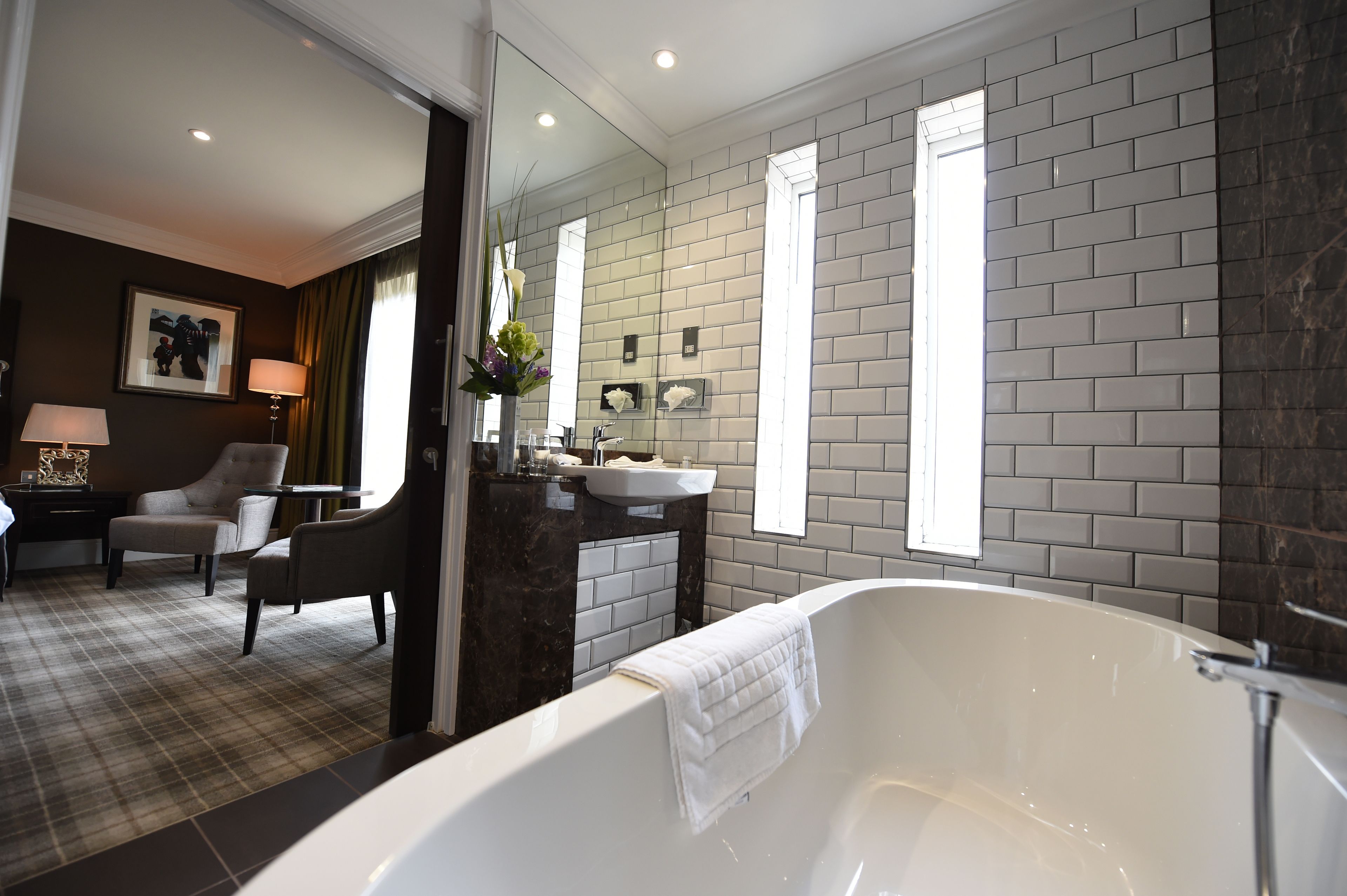 A modern bathroom with a large bathtub, a vanity with a sink, and a mirror.