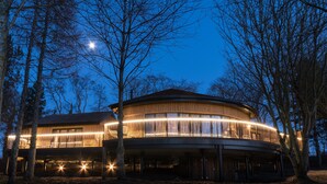 A modern, circular building with a balcony and illuminated interior lights, surrounded by trees. - Ramside Hall Hotel, Golf and Spa (Durham)
