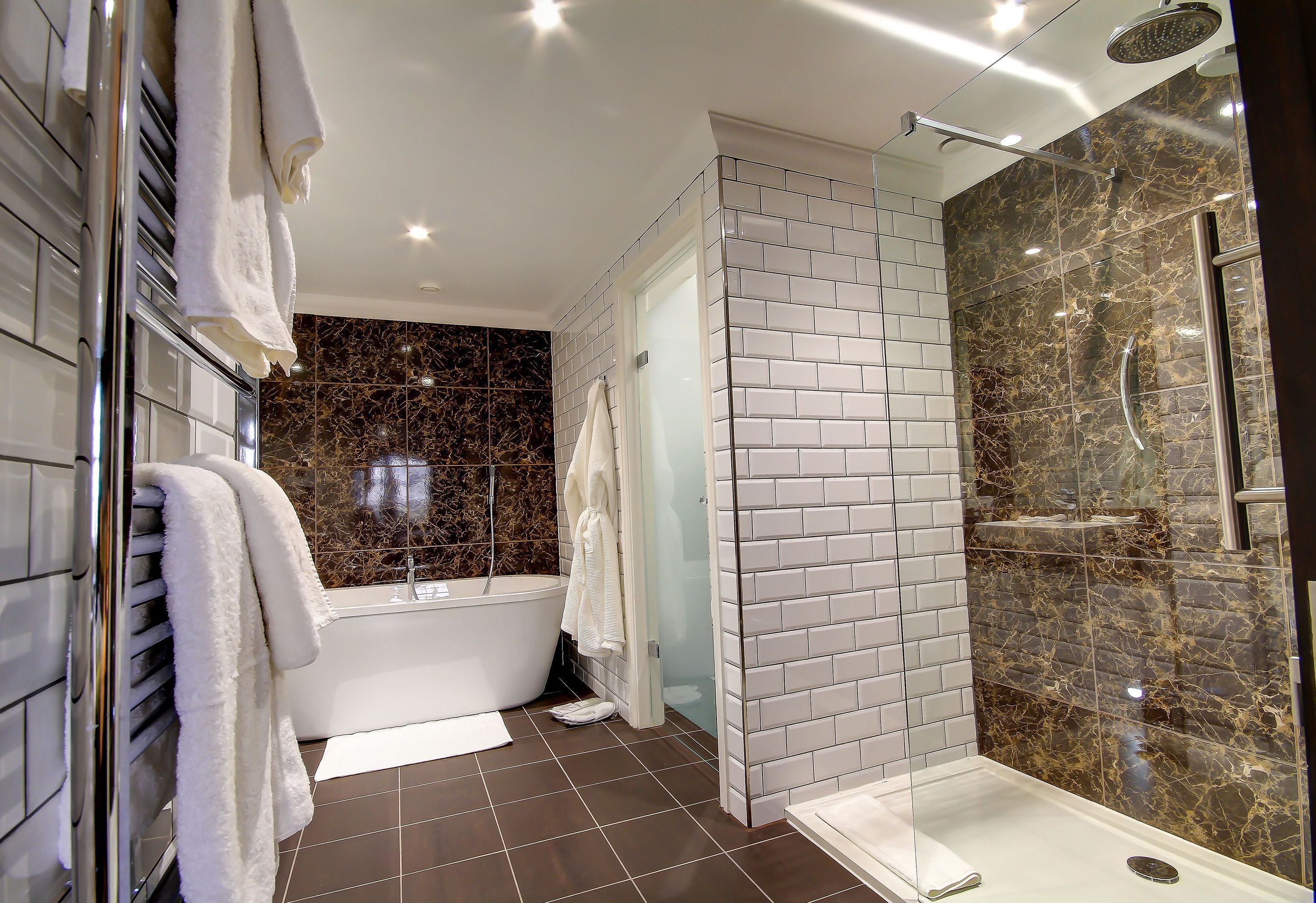 A modern bathroom with a bathtub, a glass-enclosed shower, and white tiled walls.