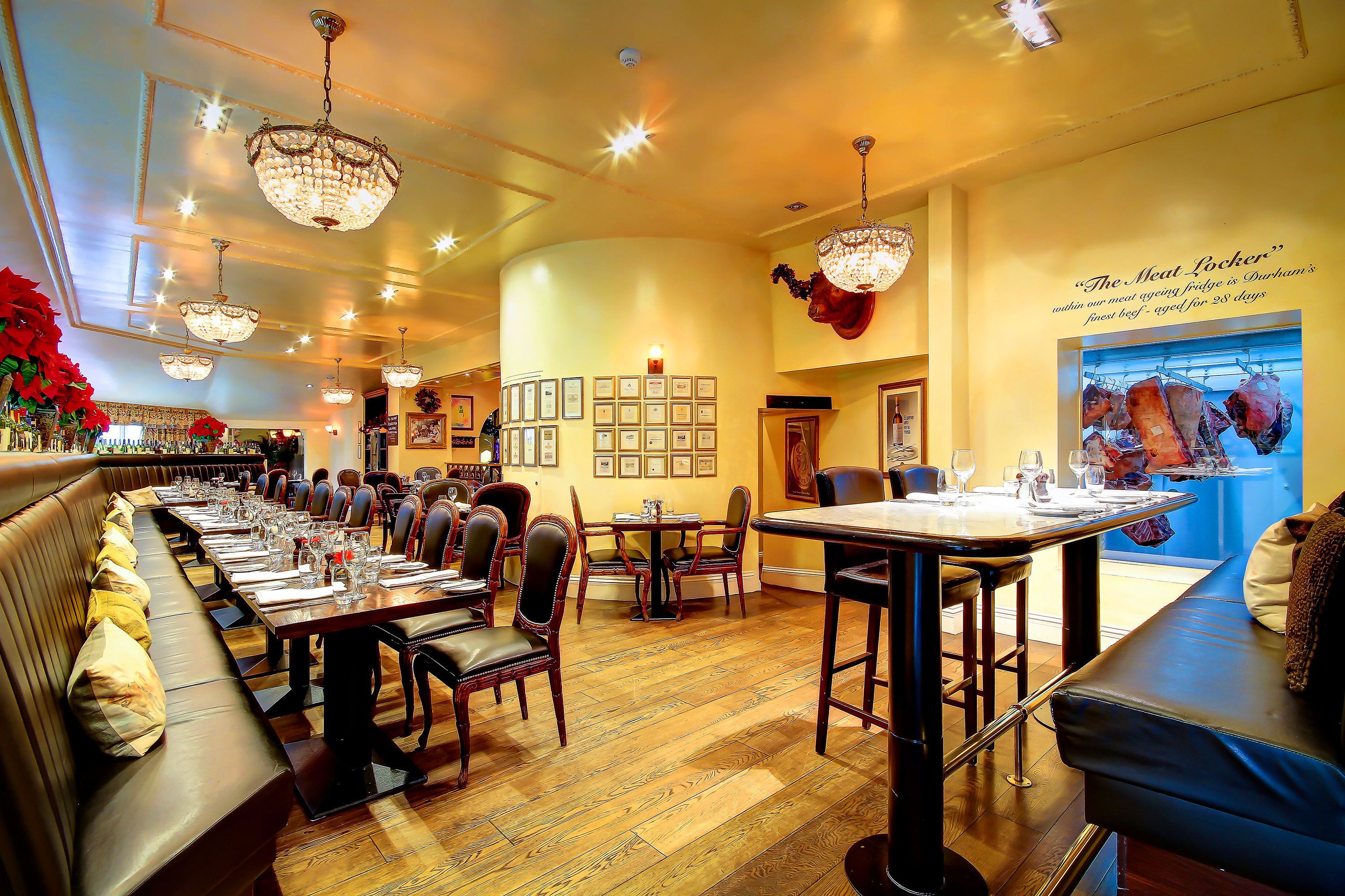 A restaurant with a long communal table, individual booths, and a bar area.