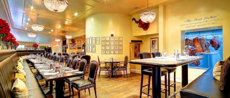 Um restaurante com uma mesa comunitária grande, cabines individuais e um espaço de bar.