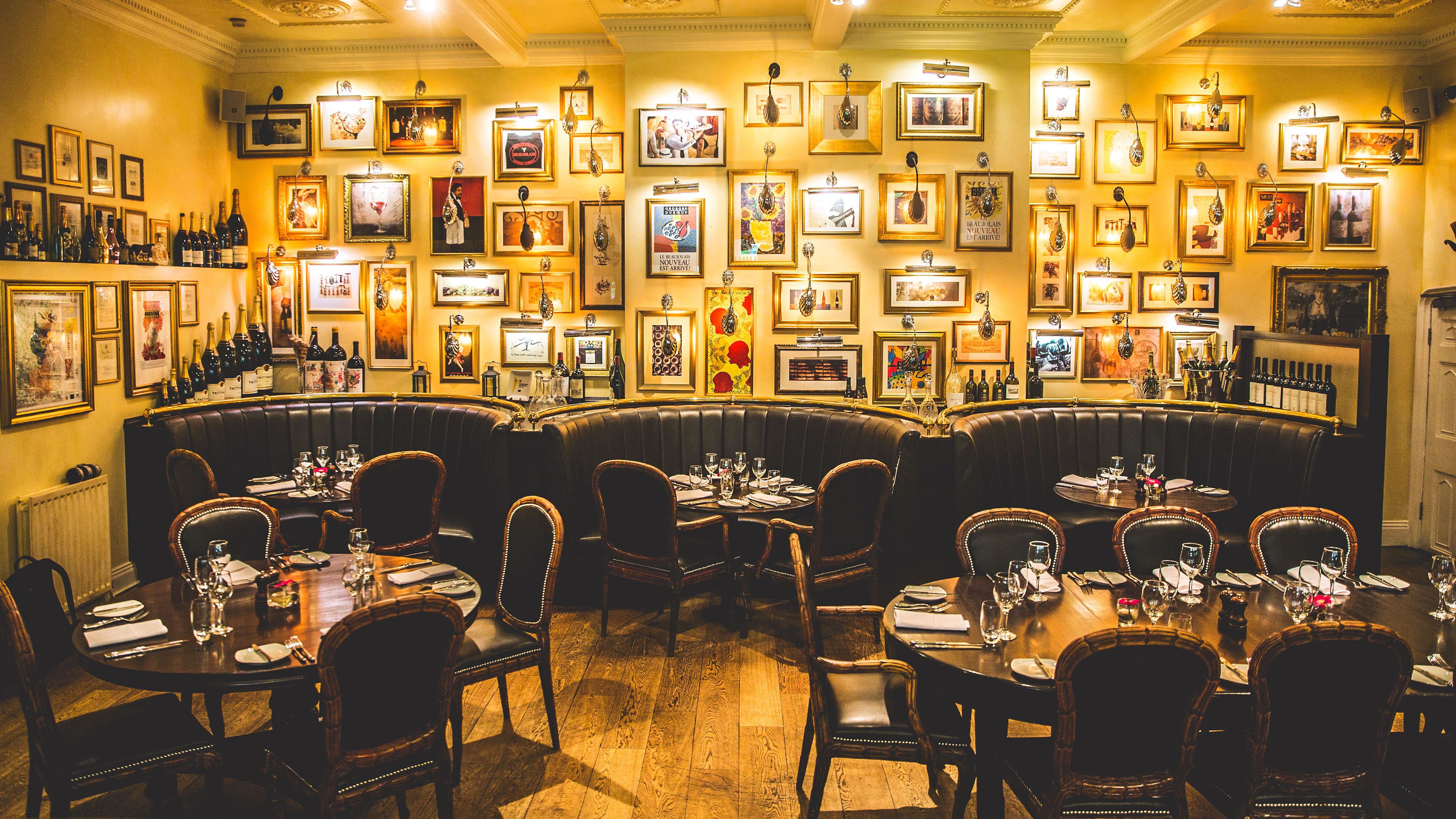 A restaurant with a bar area, multiple framed pictures on the walls, and leather booths.