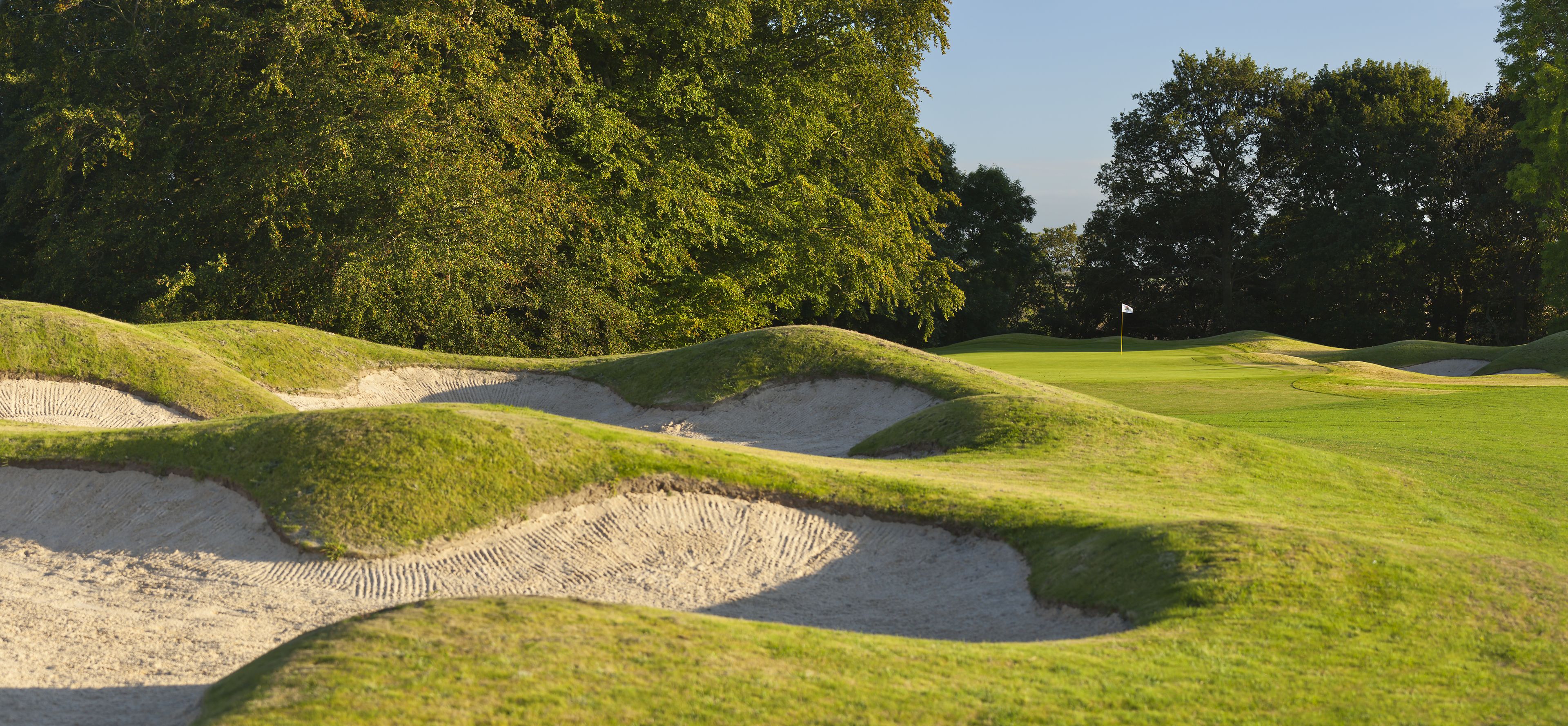 Un parcours de golf avec des bunkers de sable et un mât de drapeau.