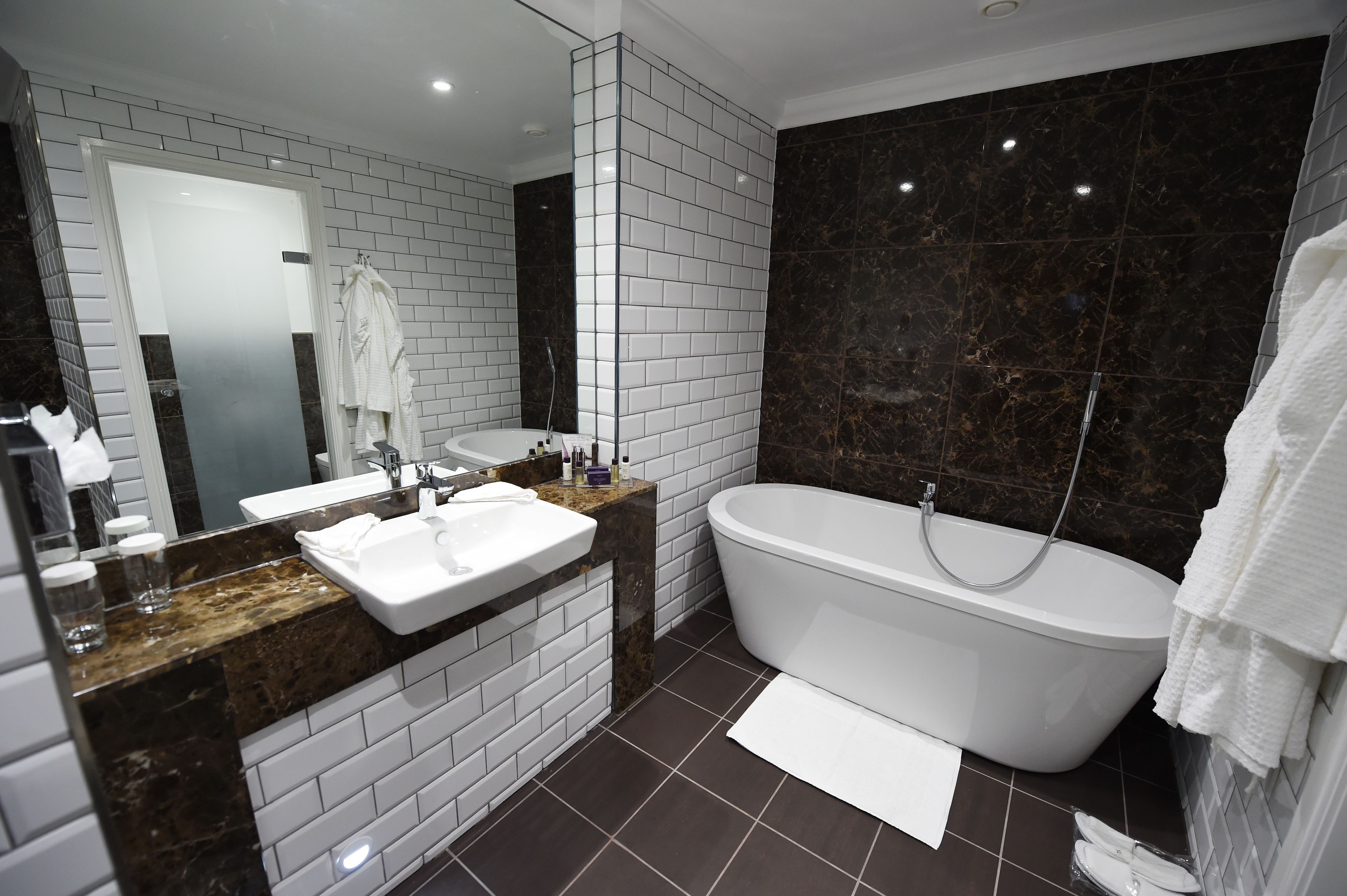 A modern bathroom with a white sink, a freestanding bathtub, and a large mirror.