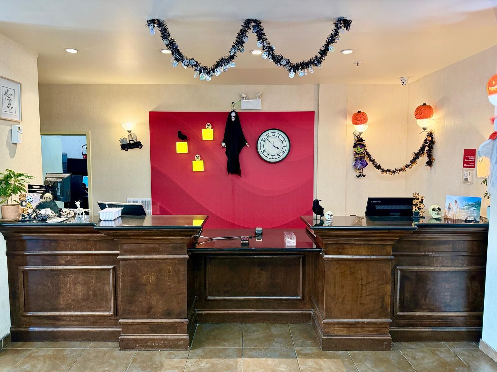 A reception desk with a red backdrop, a clock, and Halloween decorations.