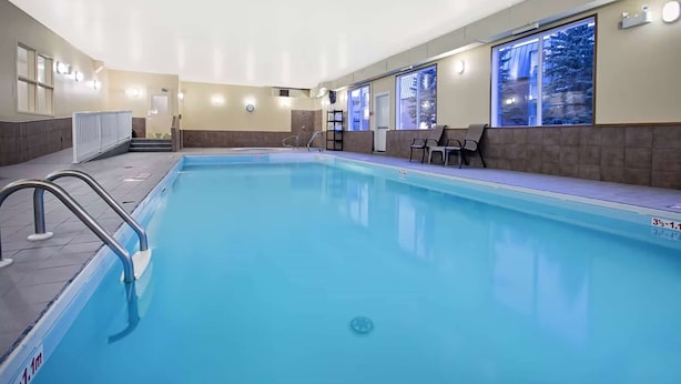 An indoor swimming pool with clear water, a diving board, and a seating area with chairs. - Ramada by Wyndham Prince Albert (Prince Albert)